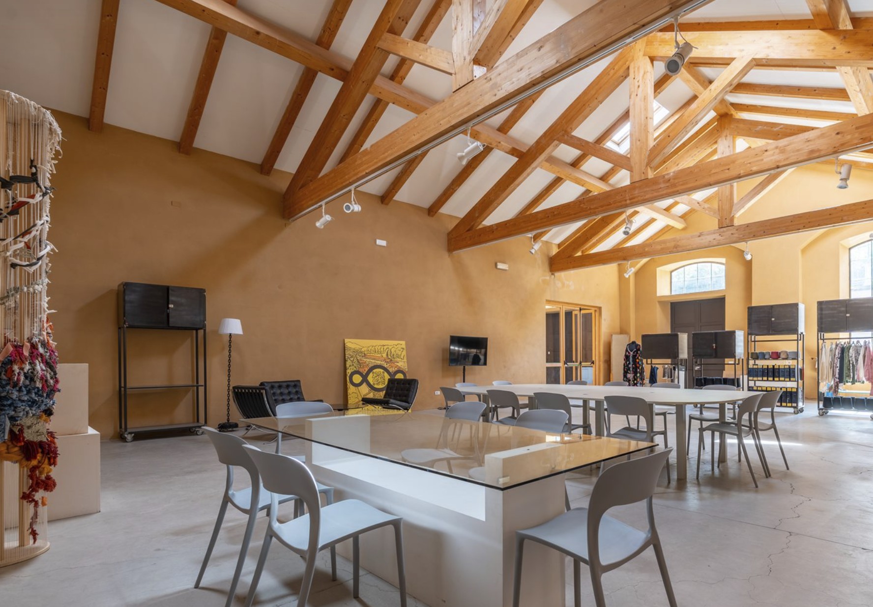 Sala Meeting con tavoli, travi in legno e luce naturale.